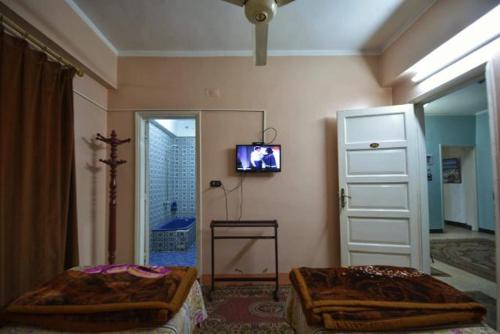 a bedroom with two beds and a tv on the wall at Fontana Luxor Hostel in Luxor