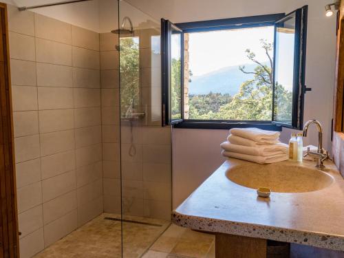 a bathroom with a sink and a shower with a window at Villa L'Arbousière in Porto-Vecchio