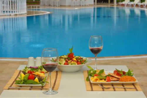 a table with two glasses of wine and a plate of food at White Hotel in Oludeniz