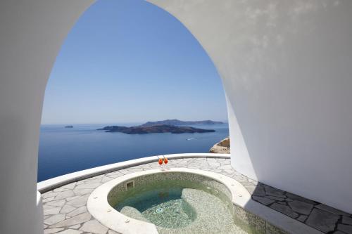 a small pool in a building with a view of the ocean at Petit Palace Suites in Fira