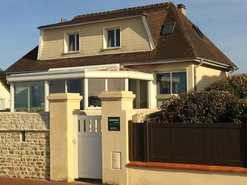 una casa blanca con una puerta y una valla en Villa lumineuse en front de mer - Gold Beach, en Asnelles