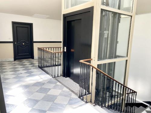 a hallway with two black doors and a checkered floor at Samourai Massena Lodge -1 min from the sea in Nice