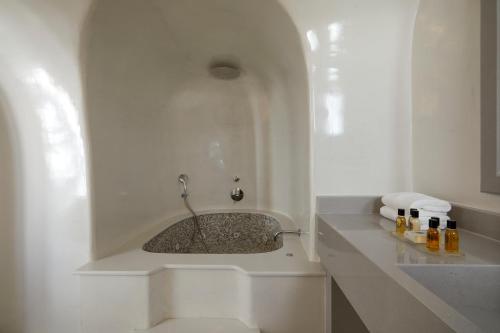 a bathroom with a sink in a white room at Petit Palace Suites in Fira