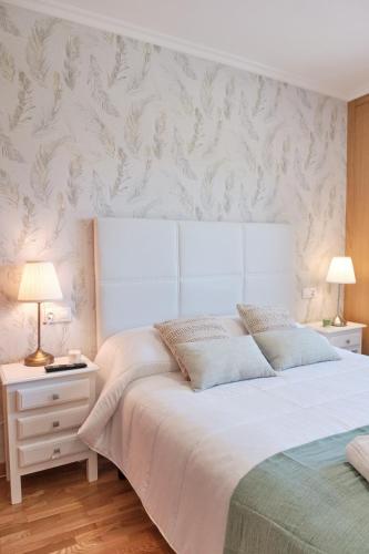 a bedroom with a large bed with a white headboard at Peregrina Pension 3 in O Pedrouzo