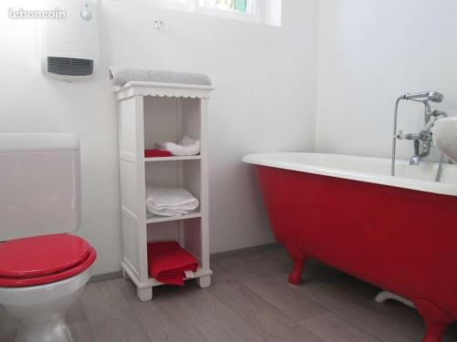 ein Badezimmer mit einer roten Badewanne und einem WC in der Unterkunft Gîte La Fabrique , spa , bain nordique in Les Fontenelles