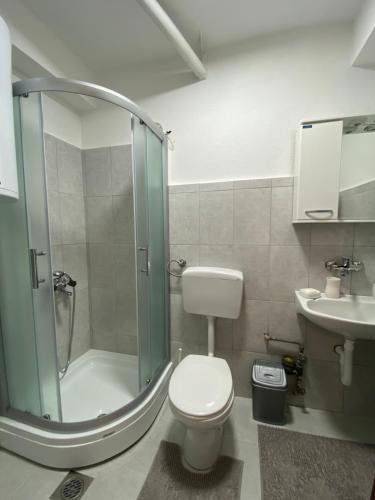 een badkamer met een douche, een toilet en een wastafel bij Sunset Apartment in Struga