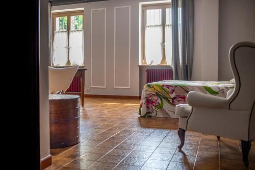 a bedroom with a bed and a chair and windows at Al Lunario in Cherasco
