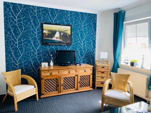 a living room with a tv and two chairs at Pension & Ferienwohnungen Schneidereit in Sassnitz