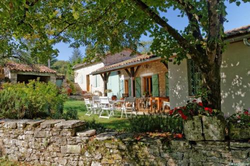 a house with chairs and a stone wall at ALABRENA in Féneyrols