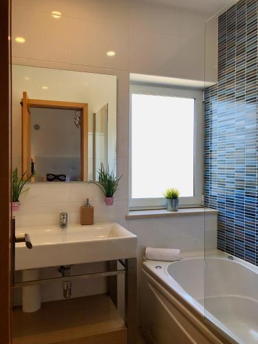a bathroom with a sink and a tub and a mirror at Âncora Boutique Apartments in Lagos
