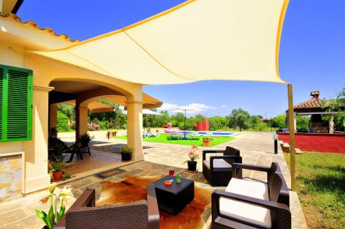 a patio with chairs and a white umbrella at Villa Mallorca Paradise in Llucmajor