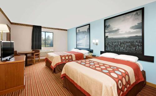 a hotel room with two beds and a flat screen tv at Super 8 by Wyndham Rock Port MO in Rock Port