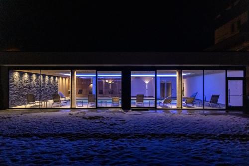 a house with a glass extension at night at Monaco Sport Hotel in Santo Stefano di Cadore