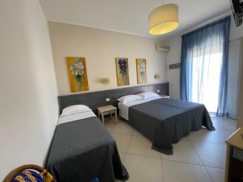 ランペドゥーザにあるAlbergo Moschellaのベッド2台と窓が備わるホテルルームです。