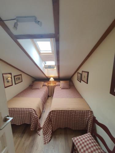 a attic room with two beds and a skylight at El Arcángel de Santillana del Mar in Santillana del Mar