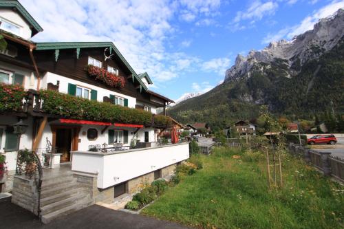 a house in a village with mountains in the background at Gästehaus Sonnenheim in Mittenwald
