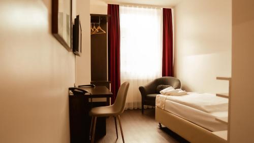 a bedroom with a bed and a desk and a window at Hotel Prens Berlin in Berlin
