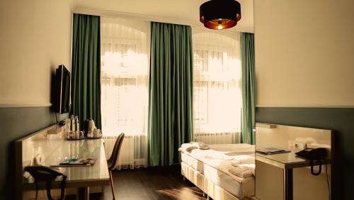 a bedroom with a bed and a desk and a window at Hotel Prens Berlin in Berlin