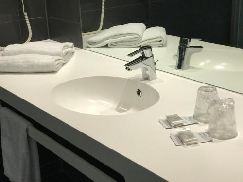 a bathroom counter with a white sink and towels at Fasthotel Montmarault in Montmarault