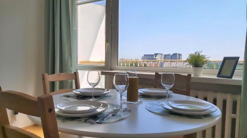 a table with plates and wine glasses and a window at ATapartments - Comfort in Gdańsk