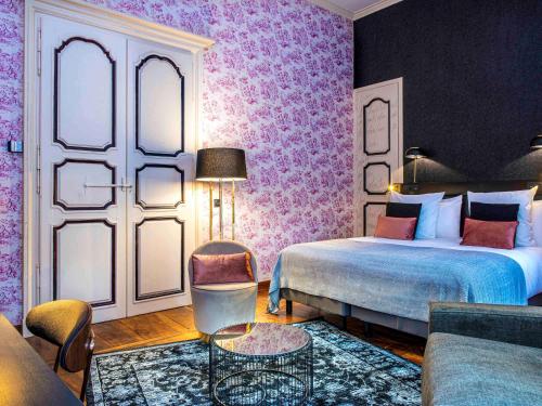 a hotel room with a bed and a couch at Mercure Figeac Viguier du Roy in Figeac