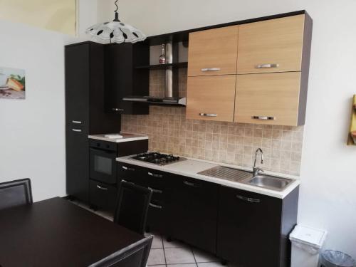 a kitchen with black cabinets and a sink at B&B Smeraldo Airport in Bergamo