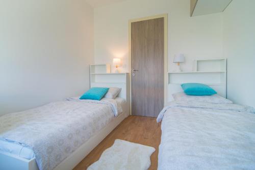 two beds in a white room with blue pillows at SUNSET VALA new beachfront apartment Pjescana Uvala - Medulin - Pula in Pješčana Uvala 