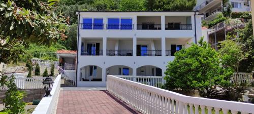 a white house with a white fence and a walkway at Zoran Apartments in Sveti Stefan