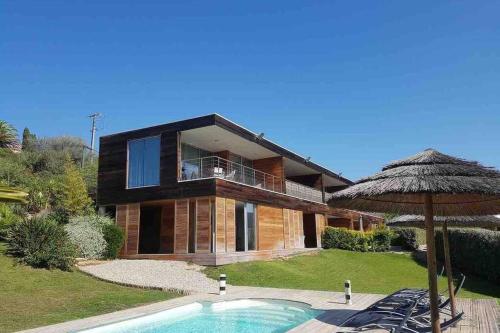 une maison avec une piscine et un parasol dans l'établissement Splendide appartement T3 piscine et vue mer, à Grosseto-Prugna