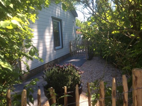 einen Garten vor einem Haus mit einem Zaun in der Unterkunft Klein geluk in Warmenhuizen