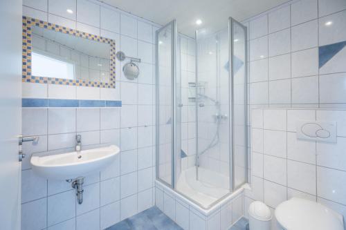 a white bathroom with a shower and a sink at Bungalow Neuwarft, Wohnung 2 in Dagebüll