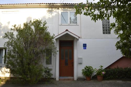 una casa bianca con una porta marrone di Apartmani Ivanka a Starigrad-Paklenica (Ortopula)