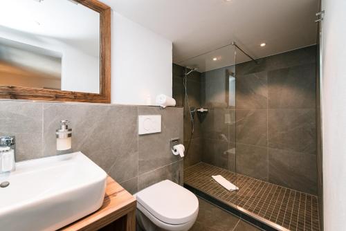 a bathroom with a shower and a sink and a toilet at Hotel Tradizio in Mittelberg