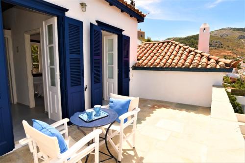 a patio with a table and chairs and a house at Villa Sunset Hydra in Hydra