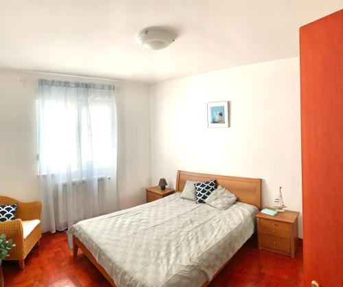 a bedroom with a bed and a chair and a window at Villa Magica in Pirovac