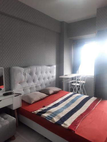 Schlafzimmer mit einem Bett, einem Schreibtisch und einem Fenster in der Unterkunft Apartement emerald bintaro 2 in Pondokaren