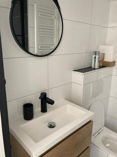 a white bathroom with a sink and a mirror at Klein geluk in Warmenhuizen