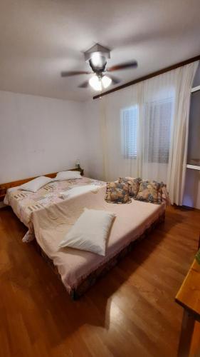 ein großes Bett in einem Schlafzimmer mit Deckenventilator in der Unterkunft Apartment PinoAppLosinj in Veli Lošinj