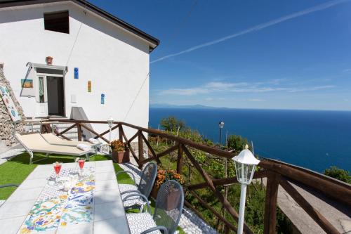 una mesa y sillas en un balcón con vistas al océano en Holidays Perla d'Amalfi, en Amalfi