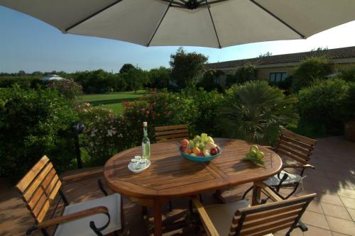 a wooden table with a bowl of fruit and an umbrella at Torre Archirafi Resort in Riposto