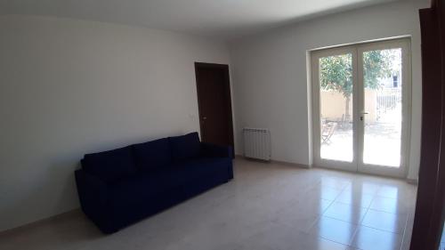 a living room with a blue couch and a sliding glass door at ArmacHouse - Appartamenti sul mare in Reggio Calabria