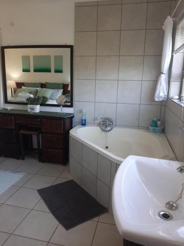 a bathroom with a tub and a sink and a mirror at Umtamvuna View Cabanas in Port Edward