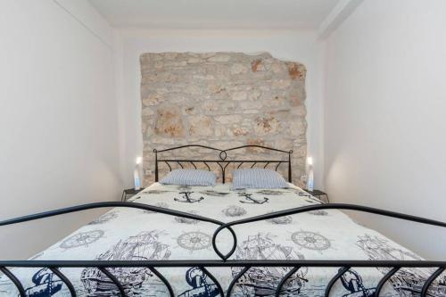 een slaapkamer met een bed met een stenen muur bij Predivan novouređeni apartman u blizini mora in Banjole