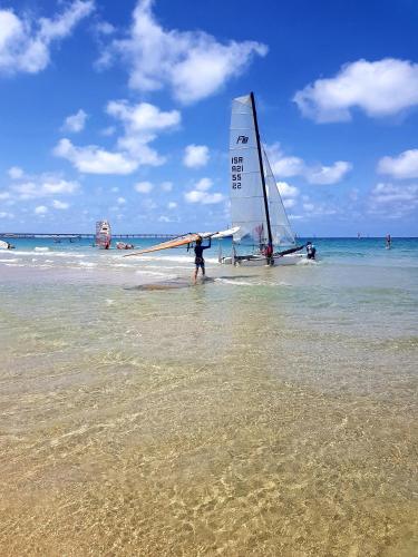 a man standing on the beach with a sail boat at neot golf kz place in Caesarea