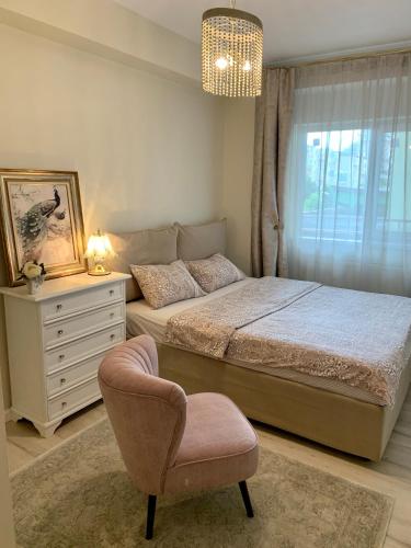 a bedroom with a bed and a chair and a dresser at Central Luxury Apartment in Alba Iulia