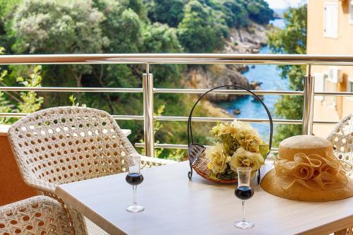 a table with wine glasses and flowers on a balcony at Apartments Misko in Utjeha