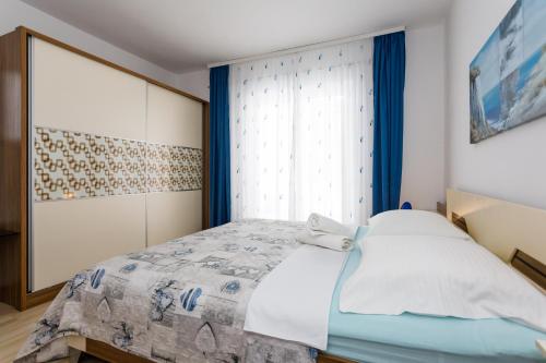 a bedroom with a bed with blue curtains and a window at Lovely Sea View House in Malinska Island Krk in Malinska