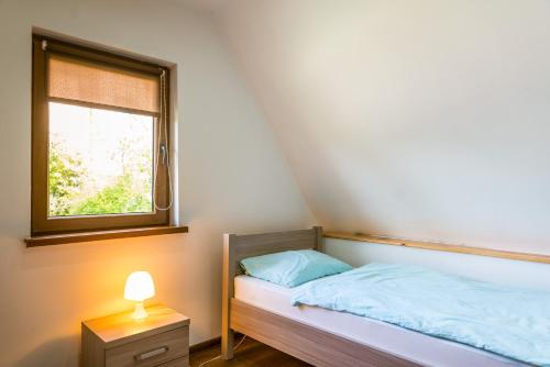 niewielka sypialnia z łóżkiem i oknem w obiekcie Domek letniskowy Słowiańska 15 w mieście Giżycko