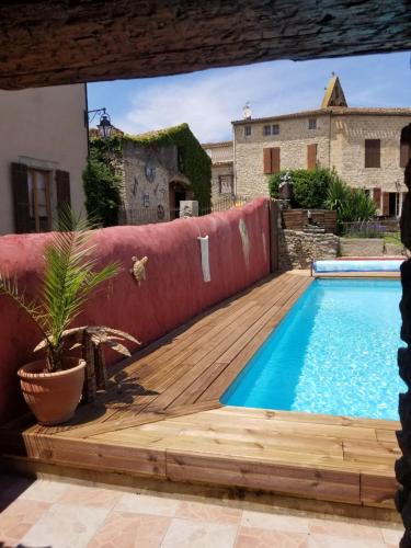 una piscina in un cortile con terrazza in legno e una pianta di Domaine du Prieuré Couvent & Presbytère a Carcassonne