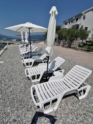 a row of white lounge chairs and an umbrella at Olea in Tivat
